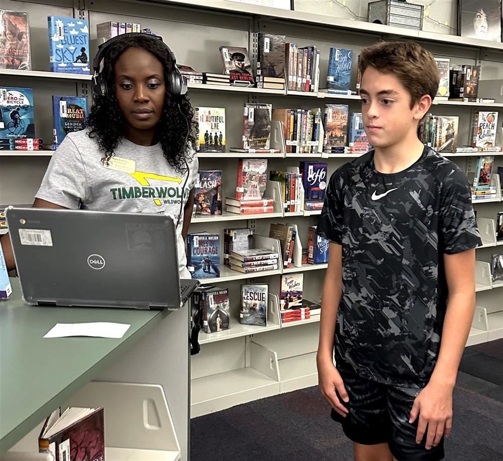  A Rockwood staff member listens to a student's digital book trailer in the school library.